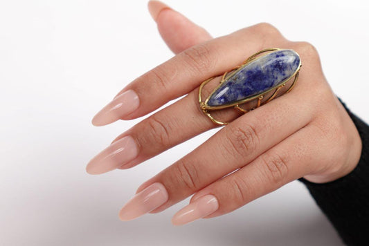 Hand wearing a ring with a blue stone on a white background