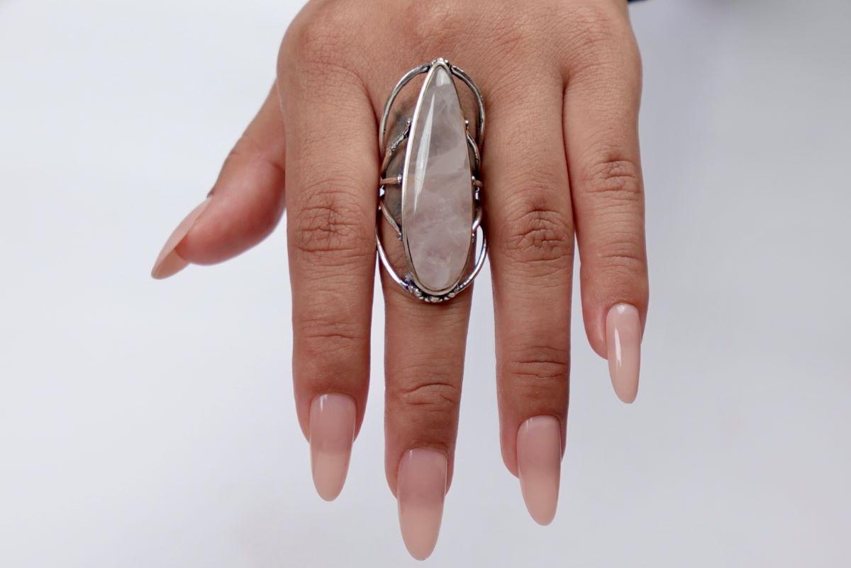 Hand wearing a large ring with a clear stone on a white background