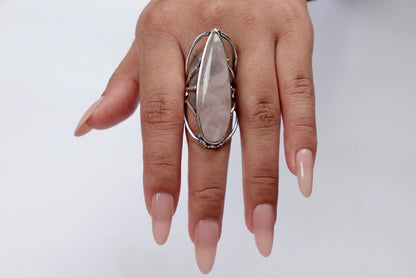 Hand wearing a large ring with a clear stone on a white background